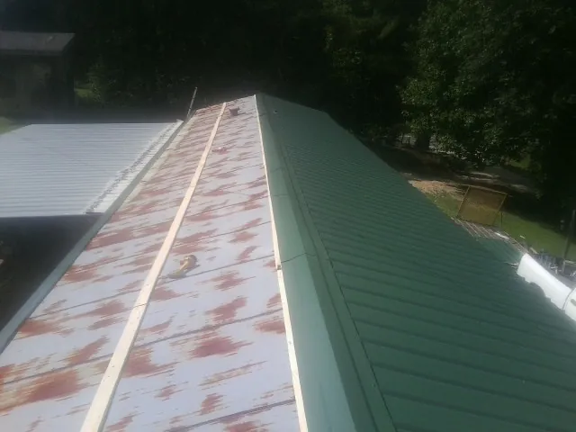 Old rusted panels beside newly installed green metal roofing — Wind Damage Roof Repair by Roofing Brothers in Waseca