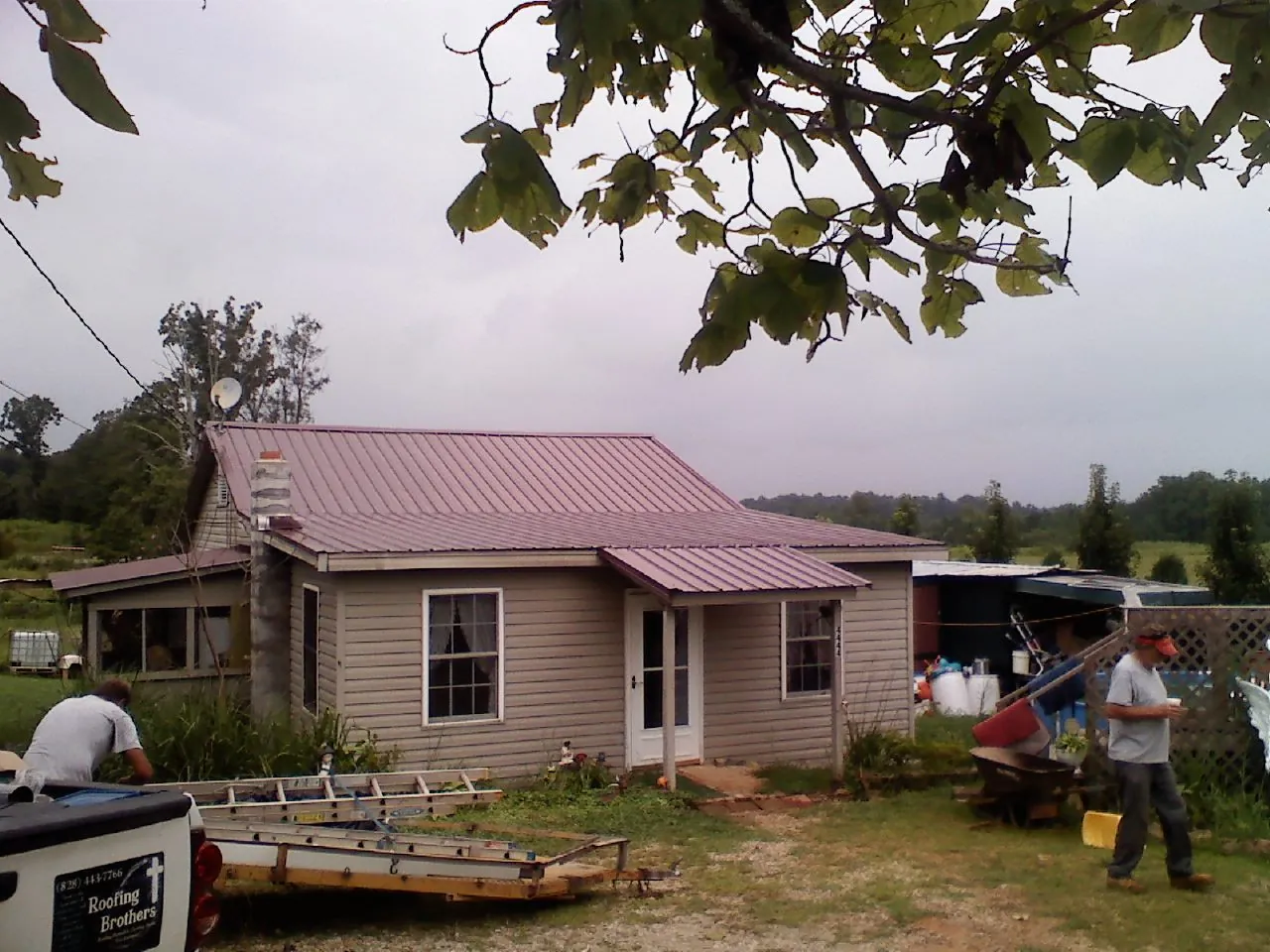 Crew finishing a mauve metal roof on a small farmhouse in Waseca
