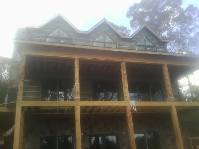 Dormers and porch framing on a large log home under construction — Roof Coating work by our crew in Waseca