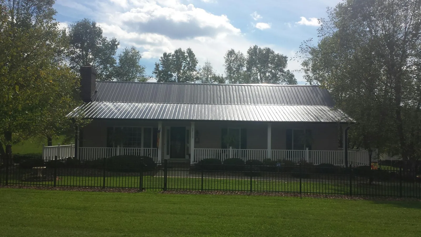 Gray metal roof on a brick ranch with a full width front porch — Gutter Guard Installation work by our crew in Waseca