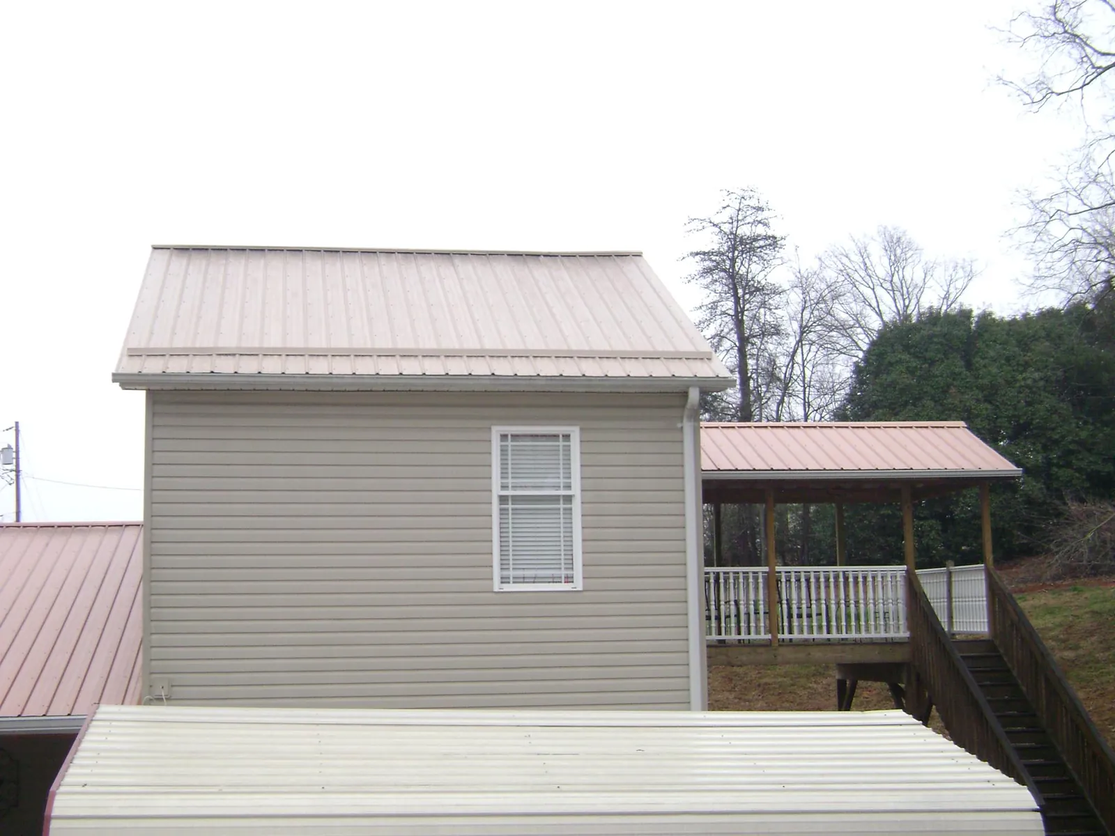Tan metal roofs on a two story addition and attached porch, from a Roof Replacement job in Waseca