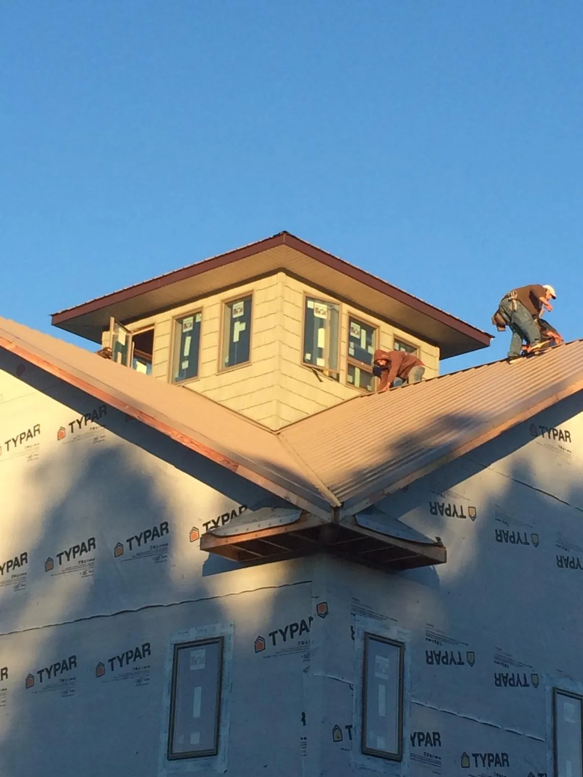 Roofers working around a rooftop cupola on a new metal roof at sunset — Roof Waterproofing in Waseca by Roofing Brothers
